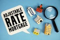 ARM Adjustable-Rate Mortgage text with house models on blue background Royalty Free Stock Photo