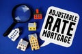 ARM Adjustable-Rate Mortgage text with house models and magnifying glass on blue background Royalty Free Stock Photo