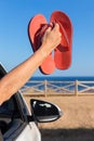 Arm in car showing bath slippers at sea