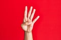 Arm of caucasian white young man over red isolated background counting number 4 showing four fingers Royalty Free Stock Photo