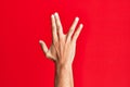 Arm of caucasian white young man over red isolated background greeting doing vulcan salute, showing back of the hand and fingers, Royalty Free Stock Photo