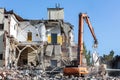 Arm of a demolition machine grab part of concrete wall