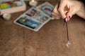 Arm of dowser with hand-held pendulum on the background of tarot cards. Royalty Free Stock Photo
