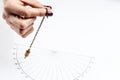 Arm of dowser with hand-held pendulum over the chart. Royalty Free Stock Photo