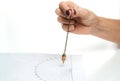 Arm of dowser with hand-held pendulum over the chart. Royalty Free Stock Photo