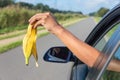 Arm dropping peel of banana out car window