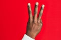 Arm and hand of african american black young man over red isolated background counting number 3 showing three fingers Royalty Free Stock Photo