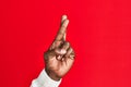 Arm and hand of african american black young man over red isolated background gesturing fingers crossed, superstition and lucky Royalty Free Stock Photo