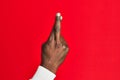 Arm and hand of african american black young man over red isolated background gesturing fingers crossed, superstition and lucky Royalty Free Stock Photo