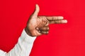 Arm and hand of african american black young man over red isolated background gesturing fire gun weapon with fingers, aiming shoot Royalty Free Stock Photo
