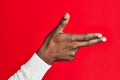 Arm and hand of african american black young man over red isolated background gesturing fire gun weapon with fingers, aiming shoot Royalty Free Stock Photo