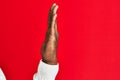 Arm and hand of african american black young man over red isolated background showing side of stretched hand, pushing and doing