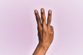 Arm and hand of black middle age woman over pink isolated background counting number 3 showing three fingers Royalty Free Stock Photo