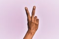 Arm and hand of black middle age woman over pink isolated background counting number 2 showing two fingers, gesturing victory and Royalty Free Stock Photo