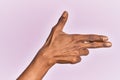 Arm and hand of black middle age woman over pink isolated background gesturing fire gun weapon with fingers, aiming shoot symbol Royalty Free Stock Photo