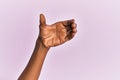 Arm and hand of black middle age woman over pink isolated background holding invisible object, empty hand doing clipping and Royalty Free Stock Photo
