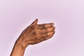 Arm and hand of black middle age woman over pink isolated background holding invisible object, empty hand doing clipping and Royalty Free Stock Photo