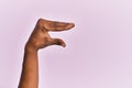 Arm and hand of black middle age woman over pink isolated background picking and taking invisible thing, holding object with Royalty Free Stock Photo