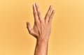 Arm and hand of caucasian man over yellow  background greeting doing vulcan salute, showing back of the hand and fingers, Royalty Free Stock Photo