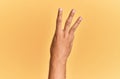 Arm and hand of caucasian man over yellow isolated background counting number 3 showing three fingers Royalty Free Stock Photo