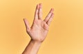 Arm and hand of caucasian man over yellow isolated background greeting doing vulcan salute, showing hand palm and fingers, freak Royalty Free Stock Photo