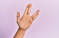 Arm and hand of caucasian young man over pink  background greeting doing vulcan salute, showing hand palm and fingers, Royalty Free Stock Photo