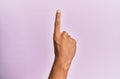 Arm and hand of caucasian young man over pink isolated background counting number one using index finger, showing idea and Royalty Free Stock Photo
