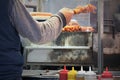 Arm of outdoor street food vendor turning meat on greasy grill Royalty Free Stock Photo