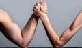 Arm wrestling. Heavily muscled man arm wrestling a puny weak man. Arm wrestling thin hand and a big strong arm in studio Royalty Free Stock Photo