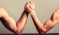 Arm wrestling thin hand and a big strong arm in studio. Two man& x27;s hands clasped arm wrestling, strong and weak, unequal Royalty Free Stock Photo