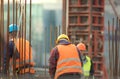 Armature and workers in orange at the construction site