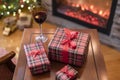 Armchair with plaid, packing gift boxes for family and glass of wine near christmas tree and fireplace. Top view.