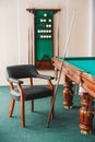 Armchair, pool table, cue in the billiard room. Royalty Free Stock Photo