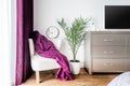 Purple blanket and a wall clock as decor in modern, stylish bedroom