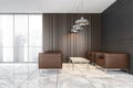 Armchairs in reception hall, grey and wooden walls and tiled floor in office