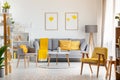 Armchairs and table in grey and yellow living room interior with