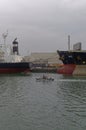 An armed Anti Piracy Patrol boat passing between 2 moored Vessels in the Port of Conakry