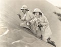 Armed couple climbing up sand dune Royalty Free Stock Photo