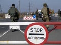 Armed Ukrainian border guards check vehicles on the security checkpoint. War in Donbass. The inscription on the road sign - Stop.