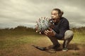 Armed civilian fighting with model of coronavirus virion outdoor on meadow