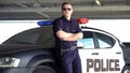 Armed policeman in sunglasses standing near patrol auto, dangerous profession