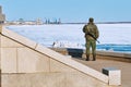 An armed Russian border guard guards the state border. View of a soldier from the back. Granite embankment of the Amur