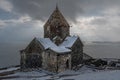 Armenia, Lake Sevan - January 9, 2026: Stone church of Sevanavank Monastery stands on snowy plateau above lake, dark Royalty Free Stock Photo
