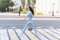 An Armenian brunette girl in elegant blue clothes crosses the road at a zebra crossing Royalty Free Stock Photo