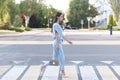 An Armenian brunette girl in elegant blue clothes crosses the road at a zebra crossing Royalty Free Stock Photo