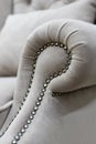 Armrest of a soft chair in a gray velvet fabric with decor made of decorative nails without people close-up