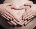 Arms both parents on pregnant mommy belly tummy heart shape Royalty Free Stock Photo