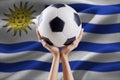 Arms holding ball with flag of Uruguay Royalty Free Stock Photo