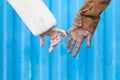 Arms of interracial couple holding hands, great love symbolic concept, blue background