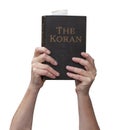 Arms raised into the air with hands reaching up holding the muslim Koran holy book of Islam